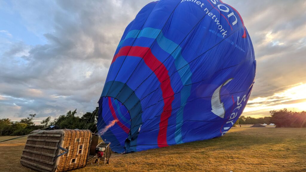 Photo of hot air balloon nearly inflated, with the burner heating the air inside