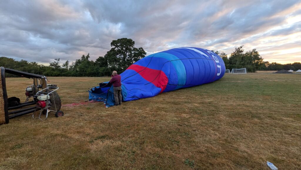 Photo of a man holding the bottom of the balloon open so that fans can blow air into it